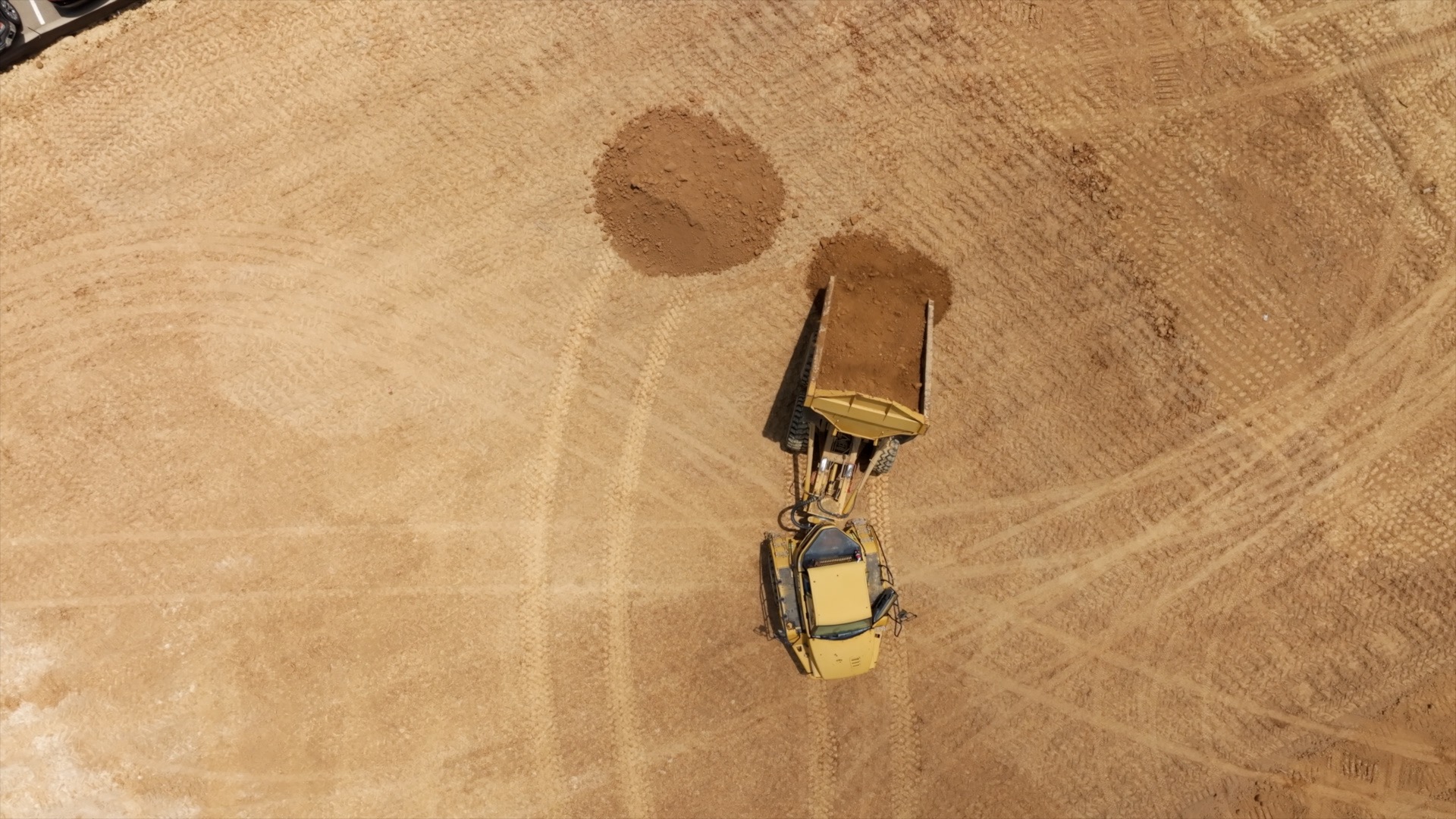 Apricot colored dirt being moved by a yellow bulldozer.