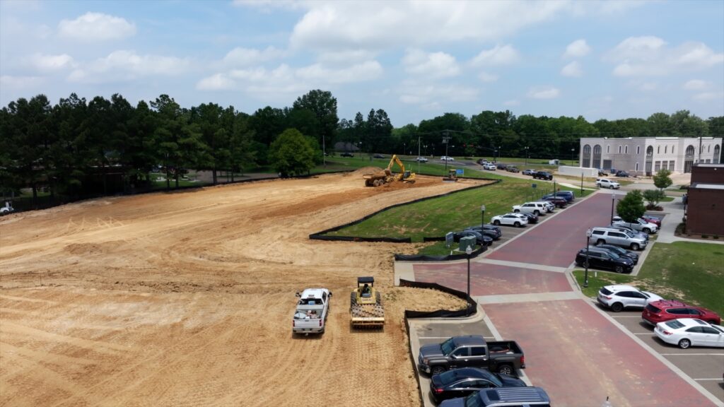 Clay colored dirt with bulldozers and brick parking lot. 